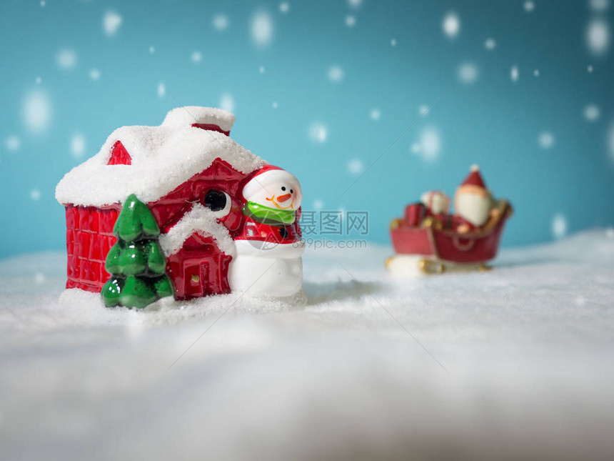 快乐的圣诞老人带着去雪屋的雪橇上的礼品盒雪屋附近有雪人和圣诞树雪地上的圣诞老人和雪屋图片