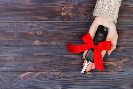 女人手握着车钥匙和红弓把车背景图片