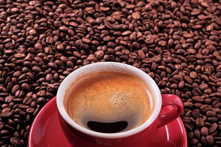 红色咖啡杯配浓咖啡和烤豆特写图片