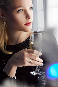 喝香槟的年轻美女待在窗户和圣诞树旁边冬家庭生活方式新年派对快图片