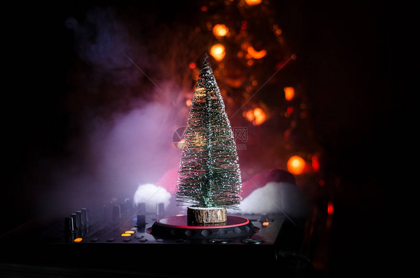 Dj混音器与耳机在黑暗的夜总会背景与圣诞树新年前夜在桌上近距离查看新年元素或符号图片