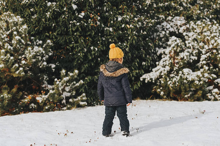 6岁男孩穿着温暖的夹克和靴子享受冬季时间背图片