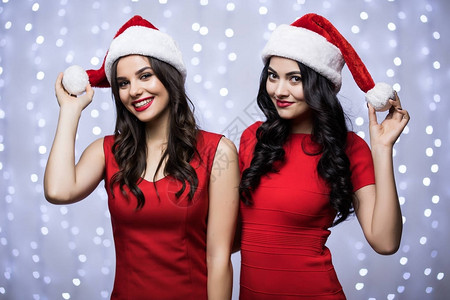 两个女人在圣诞老人的帽子和红色的衣服在散景光上的肖像寒假圣诞图片