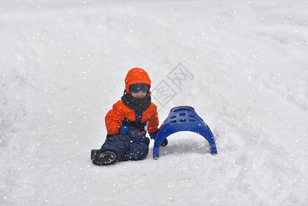 冬天骑在雪滑梯上的小男孩图片