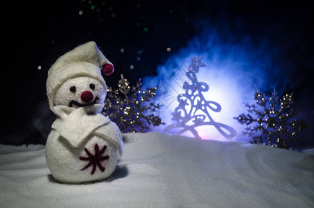 新年雪人卸下新年礼物晚上背景上被圣诞树包围的白色雪人玩具装饰图片