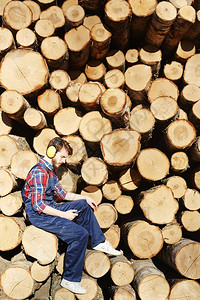 利用智能手机休息时在树干上停靠的木材切割工地作的伐木图片
