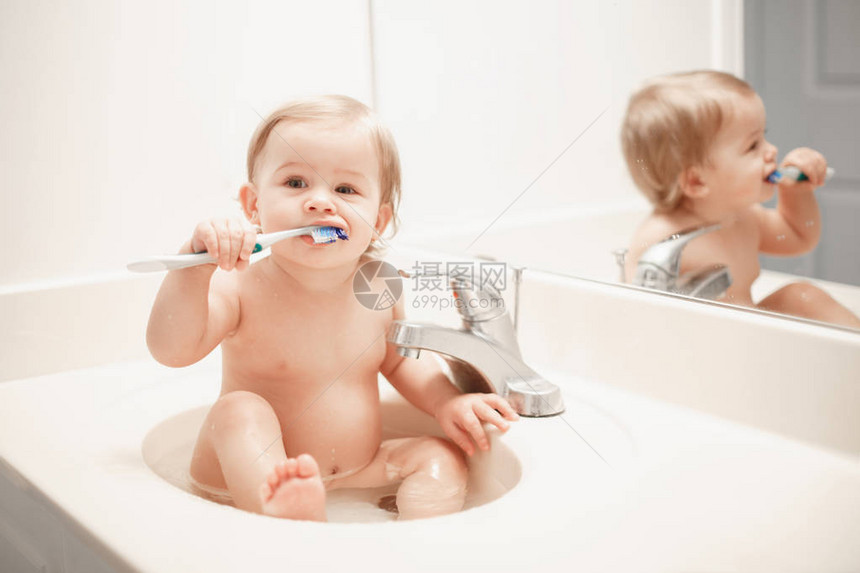 可爱的白种人金发有趣的女婴坐在洗手间水槽里的肖像孩子刷牙快乐健康的童年概念每天的家庭甜蜜时刻图片