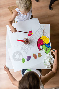 最顶端的景色是两名儿童在小白桌上画水彩画刷子图片