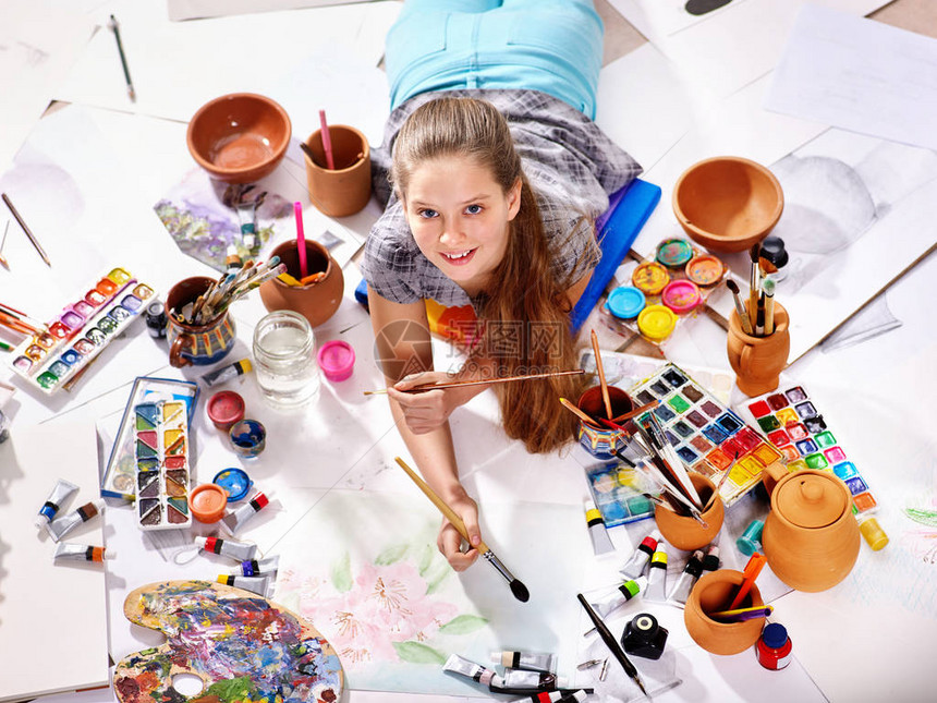 正宗的艺术家儿童女孩在早晨的阳光下用设置的调色板水彩颜料调色板和画笔绘画在地板上的工作室绘画天才儿童的顶视图片