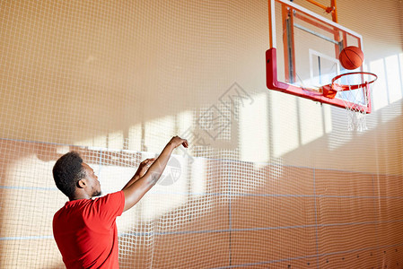 严重自信的年轻非洲裔男子投掷球篮下独自打篮球训练场图片