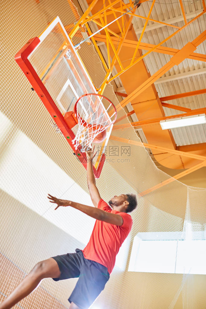 下面的观点坚定的年轻的非裔美国人篮球运动员猛扣篮跳在空中训练前比赛图片