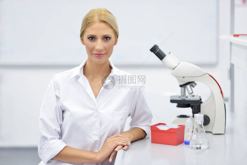 在实验室中使用显微镜的年轻科学家的肖像图片