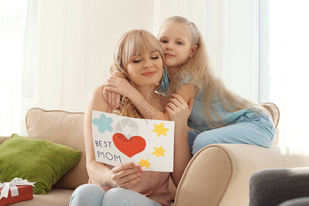 可爱的小女孩和她的母亲在家里手工贺卡的肖像图片