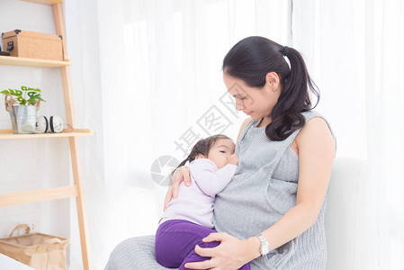 怀孕的亚洲母亲母乳喂养她的女儿在家图片