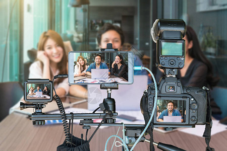 专业的相机与智能手机和动作摄像头的三脚架上的亚洲商界人士通过现场直播现场流的企业家概念背景图片