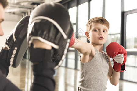 小拳击手练习拳击教练在健身房图片