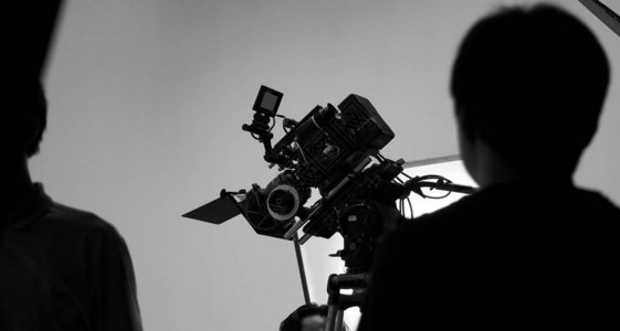 电影拍摄或视频拍摄制作的船员团队和专业设备如超级超高清数码相机与三脚架和照明设置演播室和黑白风格背景图片