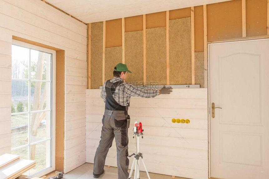 工人用一层白色木板完成墙面的抛光工作使用激光线水平用木纤维板材建筑隔热生态木框架房屋图片