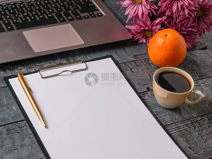 花束笔记本咖啡杯橙子和木制桌上的图片