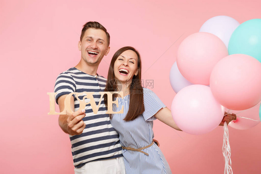肖像情侣持有木字字母的爱穿着蓝色衣服的女人和男人在粉红色的上庆祝生日派对彩色热气球人的真诚情感理念图片