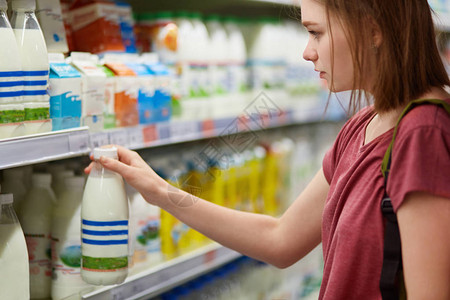 人见人爱严肃美丽的年轻女水平看法选择乳制品在超级市场的百货公司穿着休闲t恤衫有短发人生活方式和消费主义概念背景