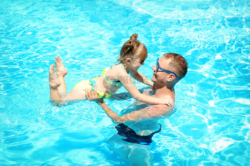 快乐的父亲与女儿在游泳池里玩耍图片