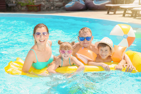 快乐家庭与充气床垫在游泳池背景图片