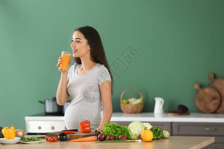 厨房里喝果汁的年轻孕妇图片