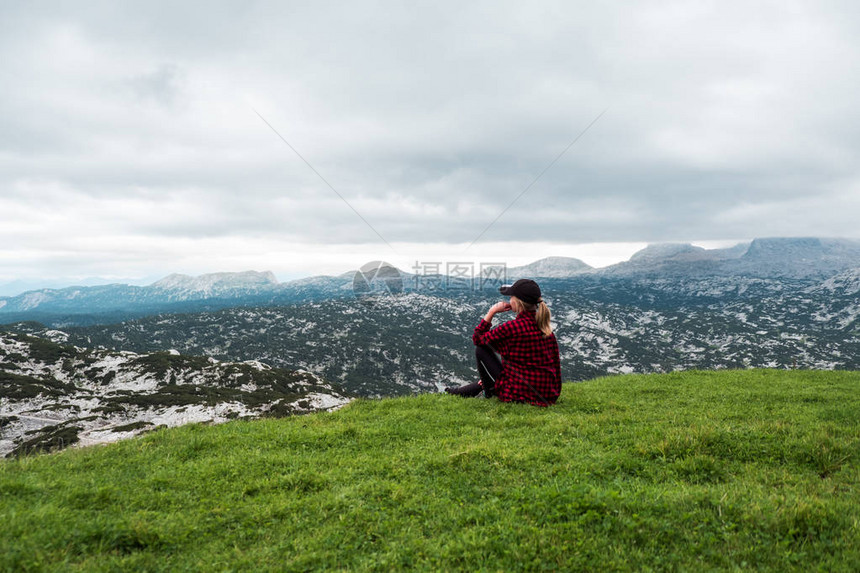 阿尔卑斯山草甸欣赏山景的年轻女子图片