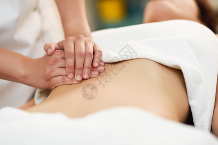 治疗师在腹部施加压力在水疗沙龙接受按摩的妇女手按摩女腹部图片