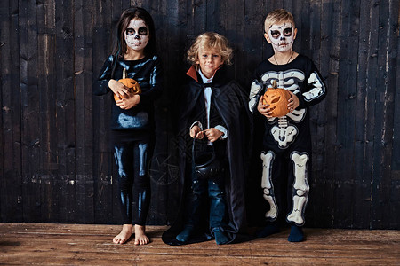 三可爱的孩子在万圣节派对在一个老房子的恐怖服装图片