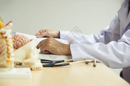 医生坐在图书馆学习课本人脑与颈椎spineand听诊器模型的研究前景背景图片