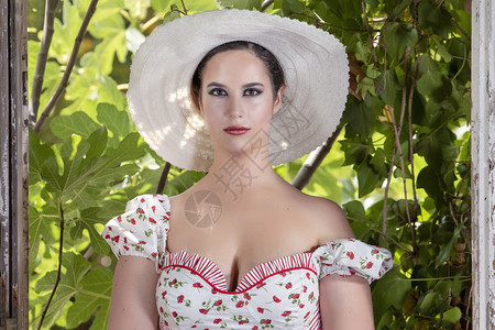 一个农村年轻女士的视图白色的礼服和的花朵和帽子在废弃的宫殿对无花果枝图片