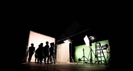 vdo制作的低关键剪影照明幕后电影摄制组团队正在设置摄像头并设置拍摄和等待电影导演同意与显示器中的场景背景图片