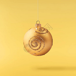 圣诞节的概念创造圣诞构想由在黄色背景上落入空气中闪亮的金色小玩意图片