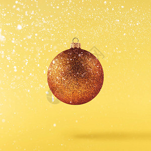 圣诞节的概念创造圣诞构想是在黄色背景下坠入空气中闪亮的小玩意图片