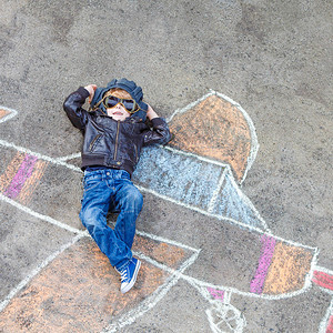 有趣的小男孩在飞机上用彩色粉笔照画飞翔图片