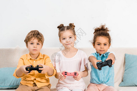 可爱的小孩子玩电子游戏与操纵杆和看相机图片