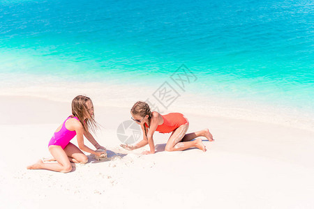 两个小快乐的女孩在热带海滩玩得很开心图片