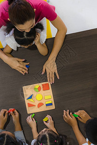 亚洲教师玩几何学区块玩具和亚洲学生一起玩的平板镜图片