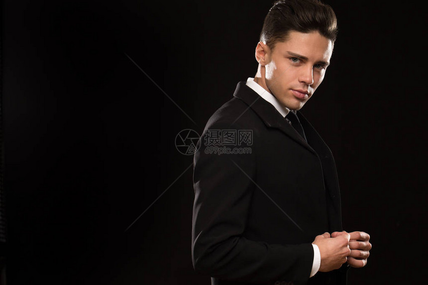 帅气感的年轻人穿着优雅优雅的黑色西装看着镜头调整着的夹克模仿空间感诱惑男子汉优雅的商人风格图片