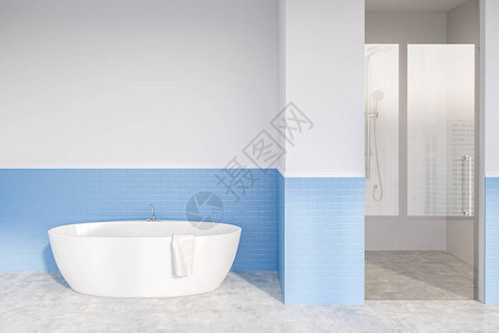 时尚浴室的内部配有白色和蓝色砖墙混凝土地板白色浴缸和带玻璃门的淋浴间图片
