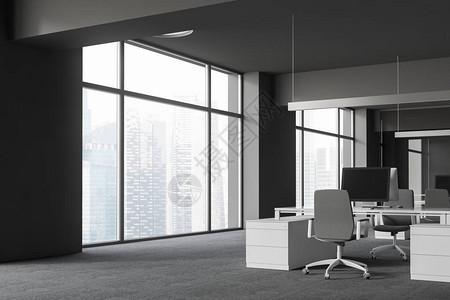 开放空间办公室的角落有灰色的墙壁和地板大窗户和带灰色椅子的白色电脑桌图片