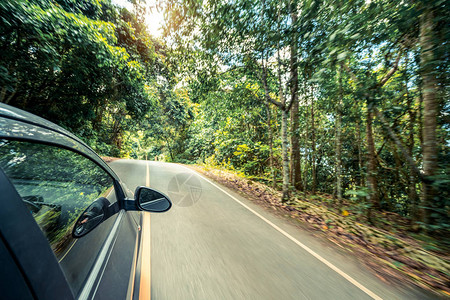 夏季在森林公路上行驶的黑色汽车的侧视图旅行和探索概念图片