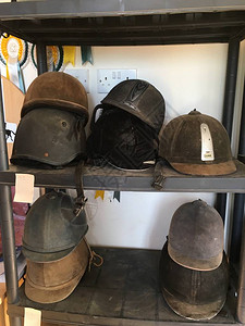 黑色骑行头盔货架上的旧头盔存放处来自马术环境的肮脏而现实的物体与图片