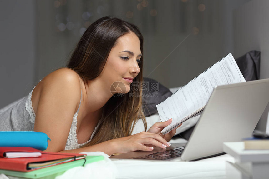 好学的学生在床上学习晚上在家拿笔记本电脑上网比较笔记图片