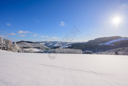 阳光明媚的蓝色冬日出在雪原和山谷上图片