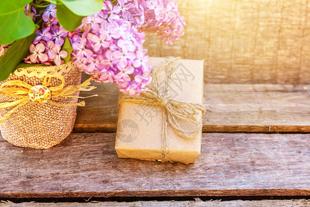 花卉装饰元素小礼品盒与礼物包裹工艺牛皮纸与花束美丽的气味紫丁香在质朴的木制背景的花背景图片