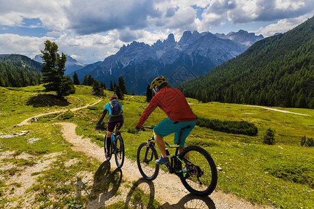 骑自行车的女人和男人骑着自行车在白云石山脉和图片