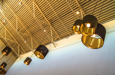 现代风格的铜质装饰灯和金色灯罩挂在长绳工业天花板背景图片